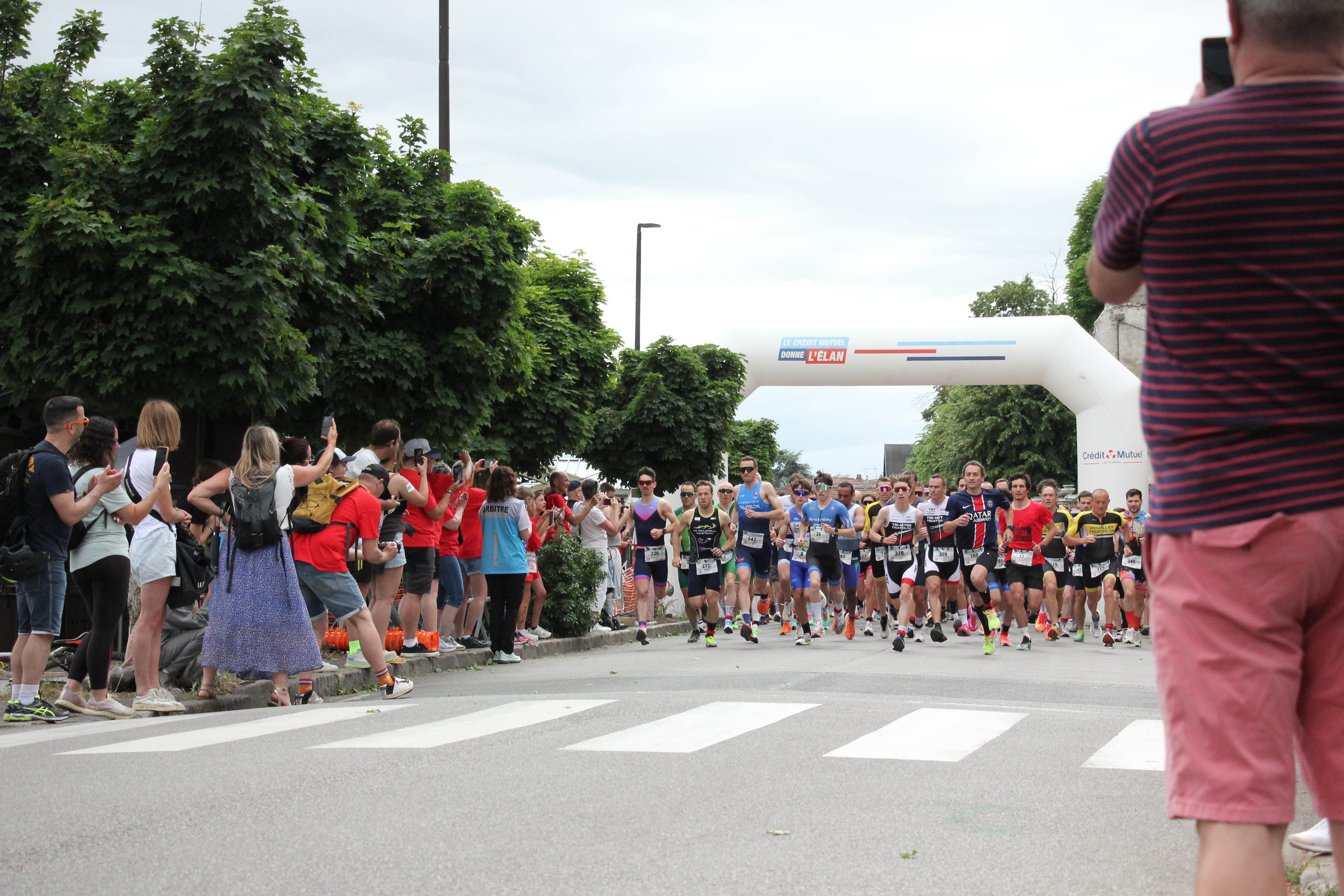 Départ du duathlon d'Andrésy 2026 sous l'arche, encouragé par le public